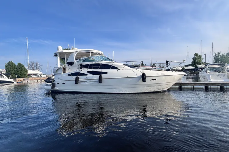The Image of 2004 Cruisers Yachts 455 Express Motoryacht docked in a marina under clear blue skies. - 0