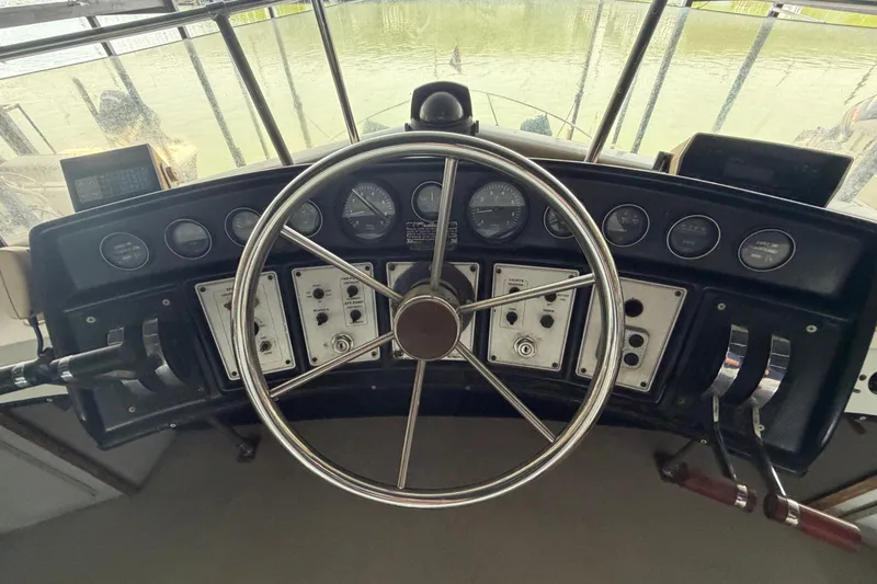 Slide: The Image of 1987 Carver 32 Aft Cabin Motor Yacht helm with steering wheel and control panels. - 11