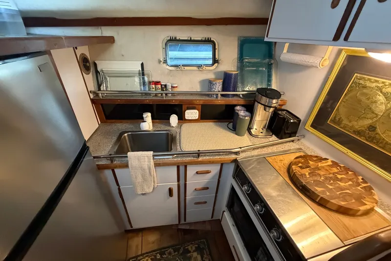 Slide: The Image of Compact kitchen in 1987 Carver 32 Aft Cabin Motor Yacht with appliances and wooden accents. - 26