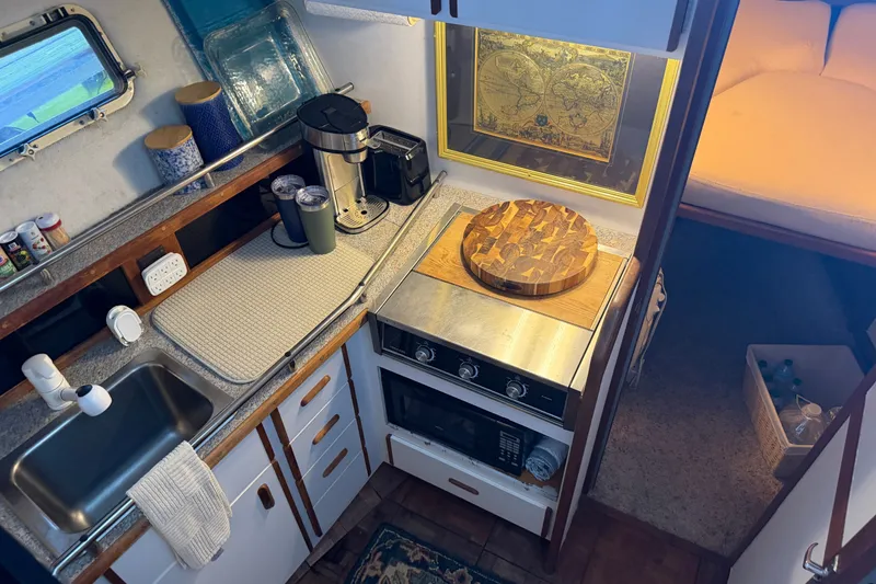 Slide: The Image of 1987 Carver 32 Aft Cabin Motor Yacht kitchen with stove, sink, and cozy cabin view. - 24