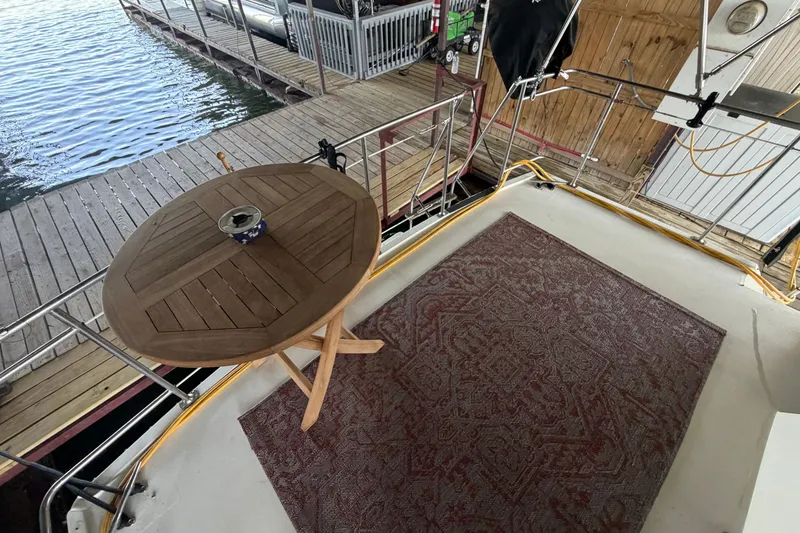 Slide: The Image of 1987 Carver 32 Aft Cabin Motor Yacht deck with wooden table and patterned rug. - 44