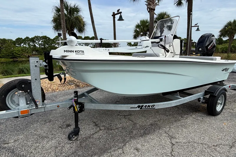 Slide: The Image of 2026 Mako Pro Skiff 13 CC boat on trailer with Minn Kota motor, parked outdoors. - 1