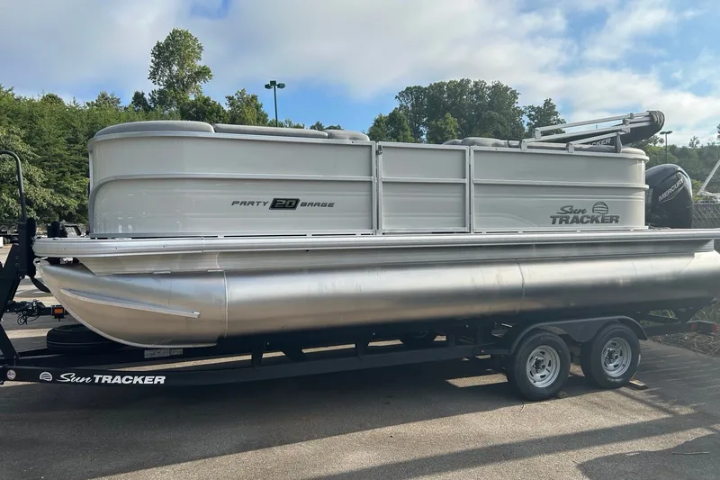 The Image of 2026 Sun Tracker Party Barge 20 DLX pontoon boat on trailer, parked outdoors. - 0