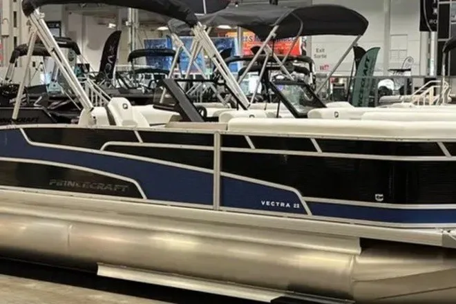 The Image of 2024 Princecraft Vectra 21 RL pontoon boat displayed indoors with sleek design and canopy. - 0