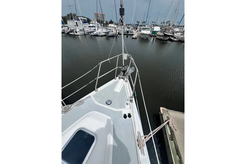 Slide: The Image of 2007 Hunter 41 Deck Salon sailboat docked in a marina, showcasing the bow and surrounding boats. - 29