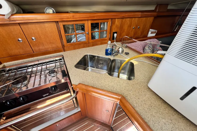 Slide: The Image of 2007 Hunter 41 Deck Salon kitchen with stove, sink, and wooden cabinetry. - 59