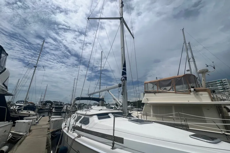 Slide: The Image of 2007 Hunter 41 Deck Salon sailboat docked at a marina under a cloudy sky. - 25