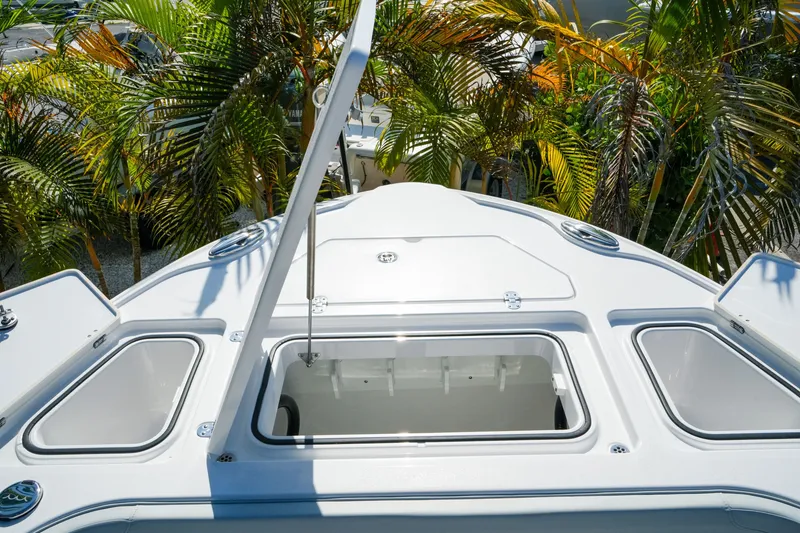 Slide: The Image of 2027 Blackfin 262 HB boat deck with open storage compartments, surrounded by palm trees. - 22