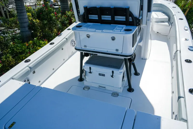 Slide: The Image of 2027 Blackfin 262 HB boat interior with coolers and seating, surrounded by lush greenery. - 7
