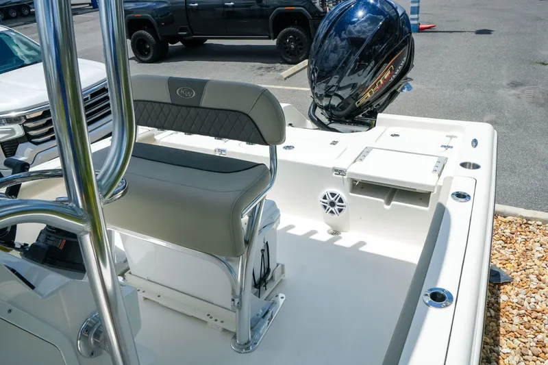 Slide: The Image of 2027 Key West 230 Bay Reef boat interior with seating and motor, parked outdoors. - 27