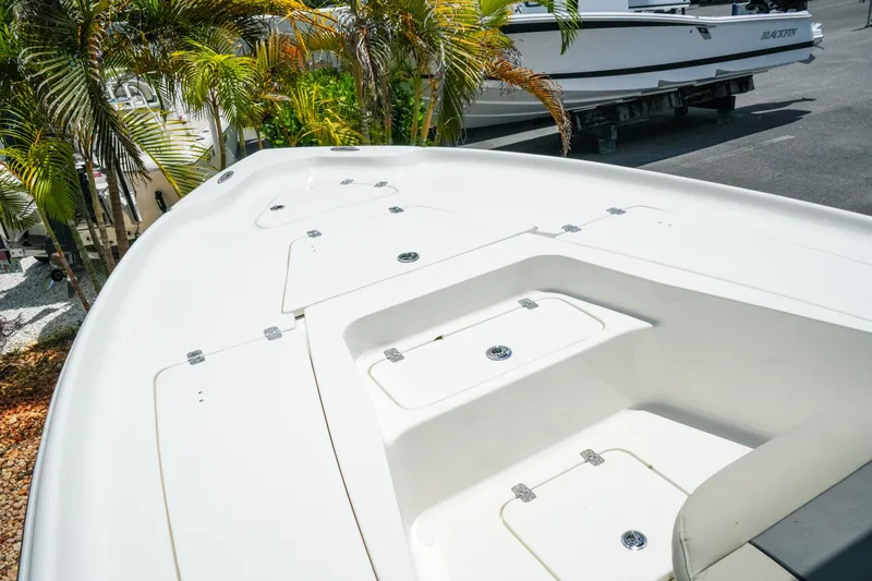 Slide: The Image of 2027 Key West 230 Bay Reef boat deck with storage compartments, surrounded by palm trees. - 18