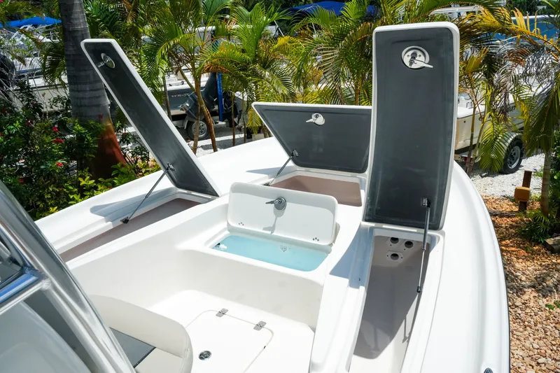 Slide: The Image of 2027 Key West 230 Bay Reef boat with open storage compartments and lush greenery background. - 19