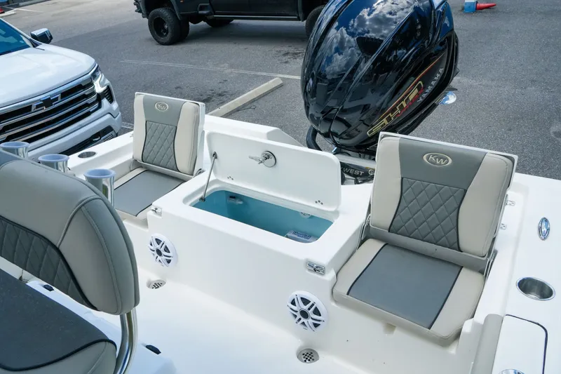 Slide: The Image of 2027 Key West 230 Bay Reef boat interior with seating, storage, and motor in a parking lot. - 32
