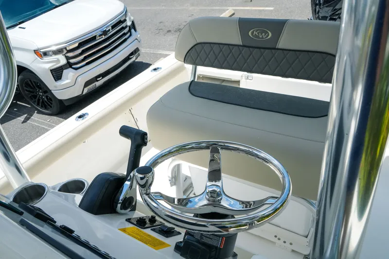 Slide: The Image of 2027 Key West 230 Bay Reef boat interior with steering wheel and seating, parked beside a white vehicle. - 26