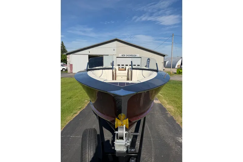 Slide: The Image of 2025 StanCraft 260 Day Boat on trailer, parked outside showroom under clear blue sky. - 30