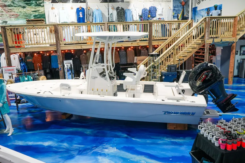 The Image of Pathfinder 2200 Hybrid 2027 boat displayed in a nautical-themed store with vibrant blue flooring. - 0