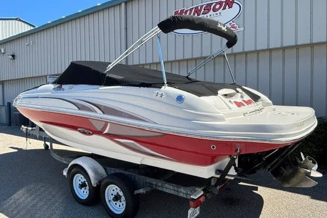 Slide: The Image of 2004 Sea Ray 200 Sundeck boat on trailer, red and white design, parked outside a marine shop. - 22
