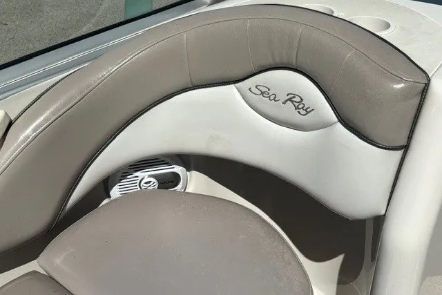 Slide: The Image of 2004 Sea Ray 200 Sundeck boat interior with beige seating and logo detail. - 10
