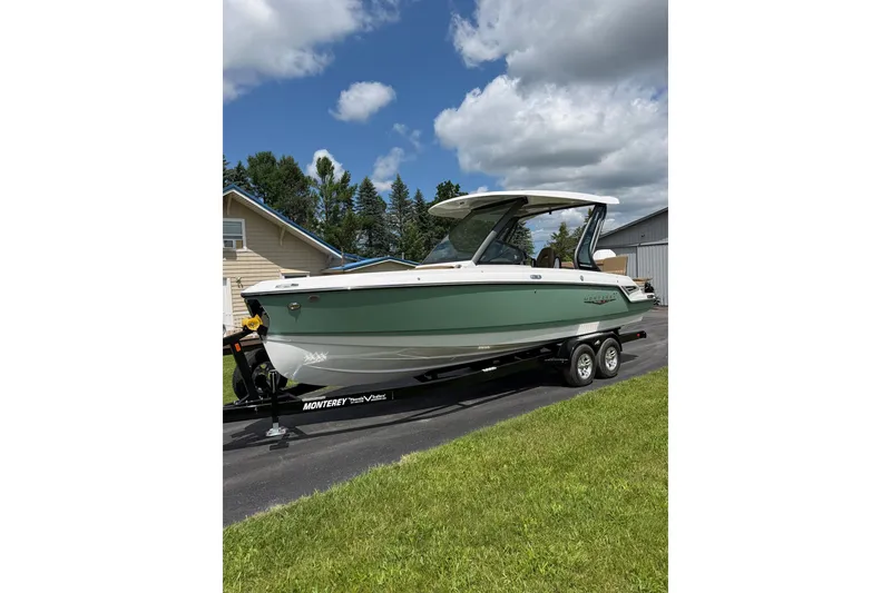 The Image of 2027 Monterey Elite 25 OB boat on trailer, parked outdoors under a cloudy sky. - 1
