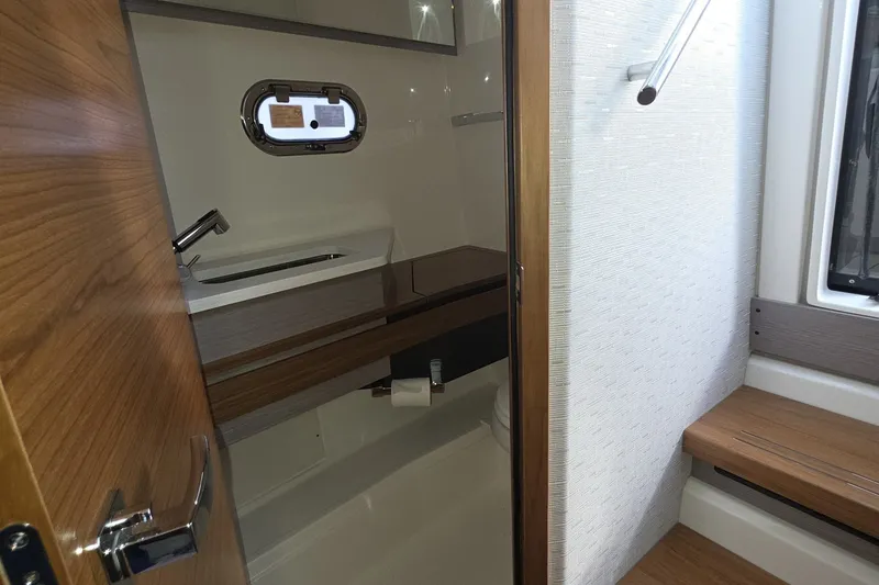 Slide: The Image of 2024 Tiara Sport 34LS boat interior bathroom with wooden accents and modern fixtures. - 17