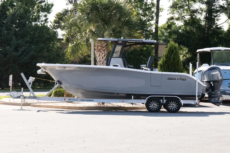The Image of 2027 Sea Pro 262 Offshore boat on trailer, parked outdoors with trees in background. - 1