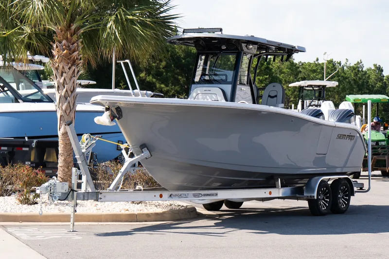 Slide: The Image of 2027 Sea Pro 262 Offshore boat on trailer, parked near palm tree. - 2