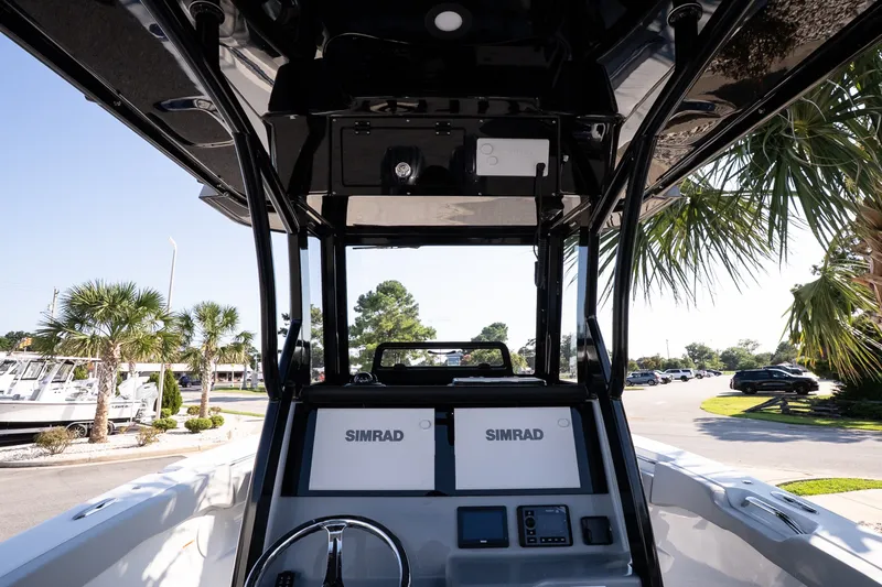 Slide: The Image of 2027 Sea Pro 262 Offshore boat dashboard with Simrad electronics, surrounded by palm trees. - 9