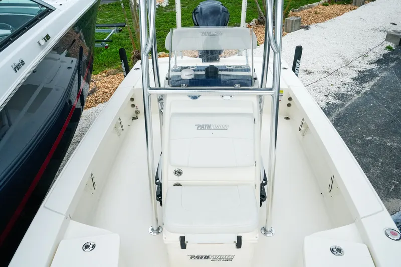 Slide: The Image of 2021 Pathfinder 2300 HPS boat interior with seating and console, docked beside another vessel. - 19