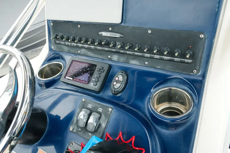 Slide: The Image of Control panel of a 2021 Pathfinder 2300 HPS boat with switches and navigation display. - 12