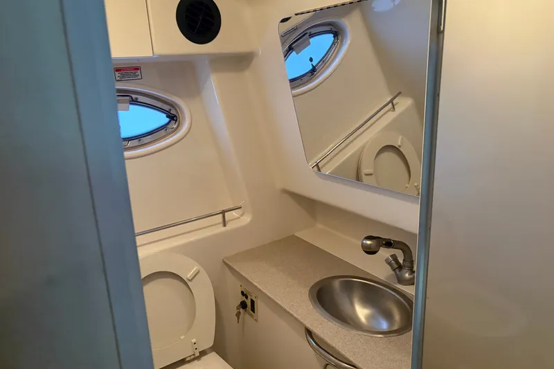 Slide: The Image of 2006 Sea Ray 290 Sundancer bathroom with sink, toilet, and porthole window. - 21