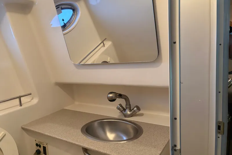 Slide: The Image of 2006 Sea Ray 290 Sundancer bathroom with sink, mirror, and porthole window. - 22