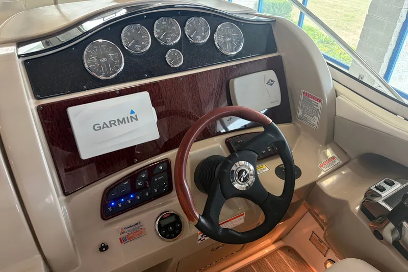 Slide: The Image of 2006 Sea Ray 290 Sundancer helm with Garmin navigation and wood-accented dashboard. - 11