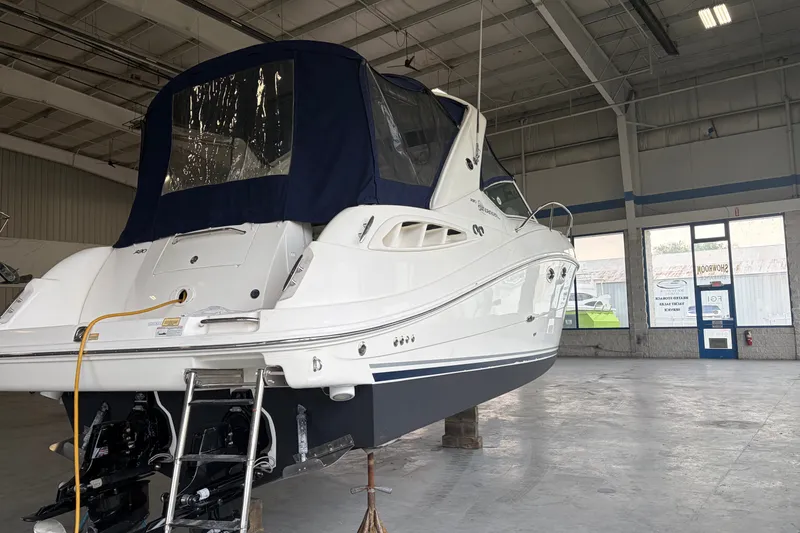 Slide: The Image of 2006 Sea Ray 290 Sundancer boat in a showroom, featuring a sleek design and blue canopy. - 3
