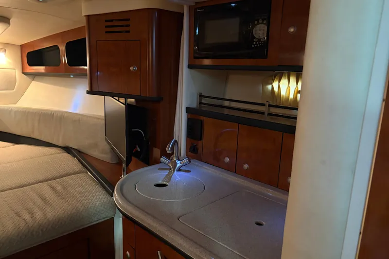 Slide: The Image of Interior of 2006 Sea Ray 290 Sundancer, featuring kitchenette and cozy sleeping area. - 18
