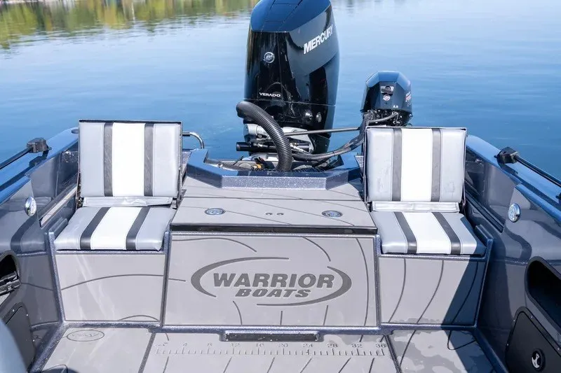 Slide: The Image of 2027 Warrior V208 boat interior with striped seats and Mercury engine on calm water. - 15