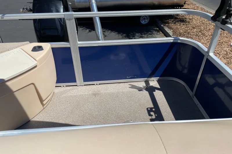 Slide: The Image of 2017 Sun Tracker Fishin' Barge 20 DLX deck area with blue paneling and beige seating. - 16
