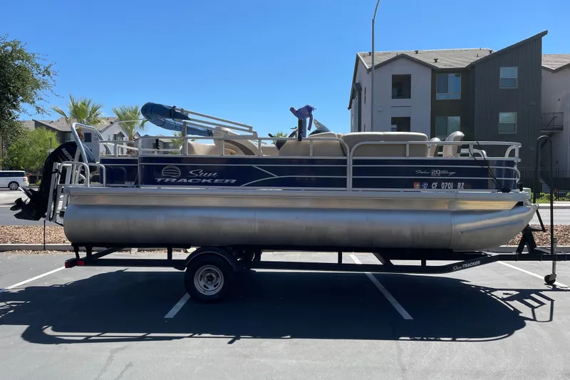 The Image of 2017 Sun Tracker Fishin' Barge 20 DLX pontoon boat on trailer in parking lot. - 0