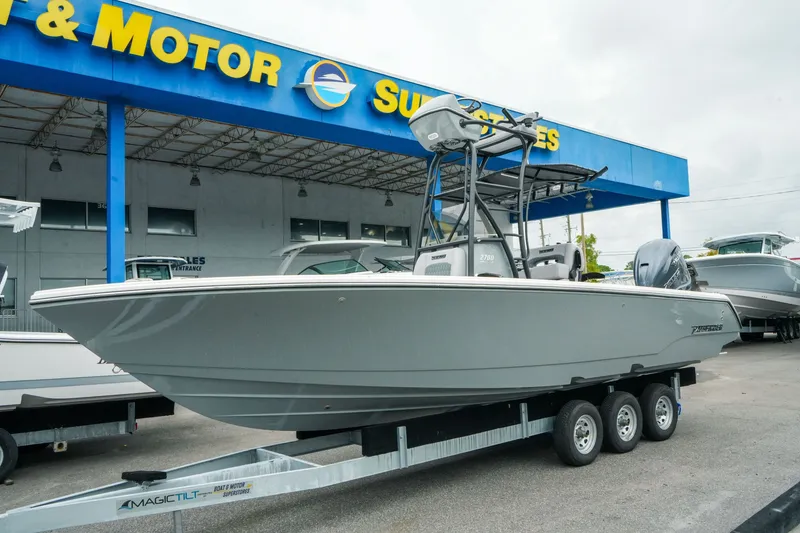 The Image of 2027 Pathfinder 2700 Tournament boat on trailer at dealership, under blue and yellow signage. - 1