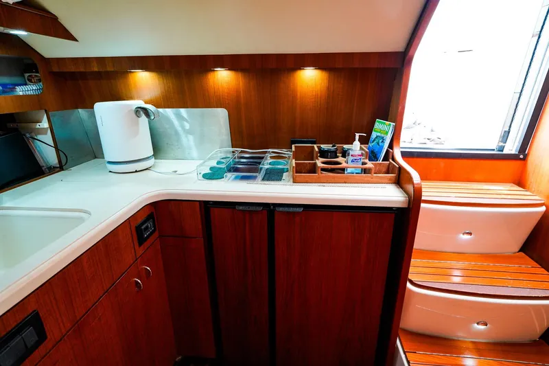 Slide: The Image of 2005 Tiara Yachts 3800 Open galley with wooden cabinetry, kettle, and countertop storage. - 25