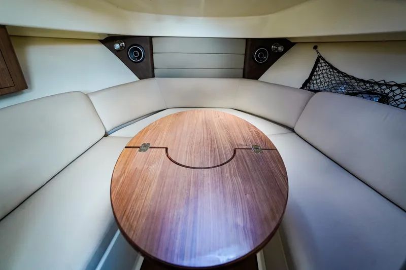 Slide: The Image of Interior of 2018 Boston Whaler 315 Conquest, featuring a cozy seating area with a wooden table. - 21