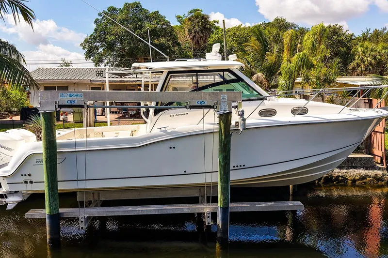 The Image of 2018 Boston Whaler 315 Conquest boat docked near lush greenery and clear skies. - 1