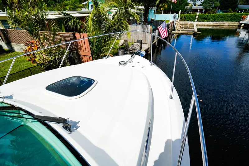 Slide: The Image of 2018 Boston Whaler 315 Conquest boat docked by a serene waterfront with lush greenery. - 27
