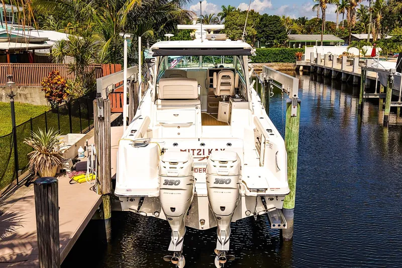 Slide: The Image of 2018 Boston Whaler 315 Conquest docked, featuring twin 350 engines, surrounded by lush greenery. - 34