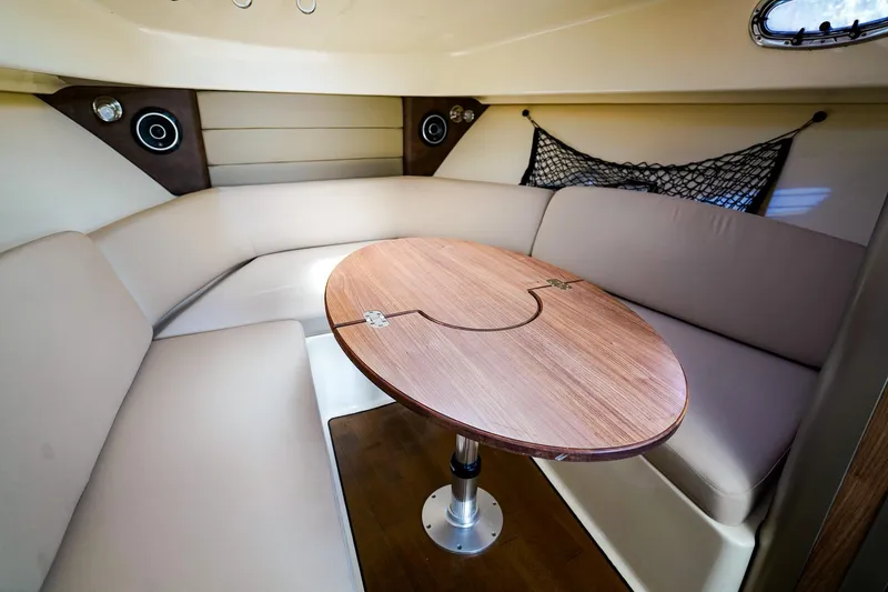 Slide: The Image of 2018 Boston Whaler 315 Conquest cabin interior with cushioned seating and wooden table. - 19