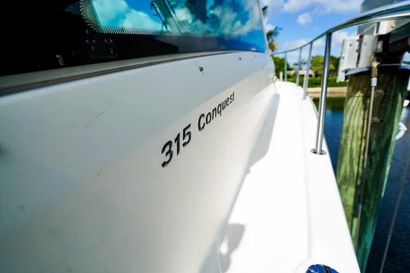 Slide: The Image of 2018 Boston Whaler 315 Conquest boat docked, showcasing sleek design and branding. - 26