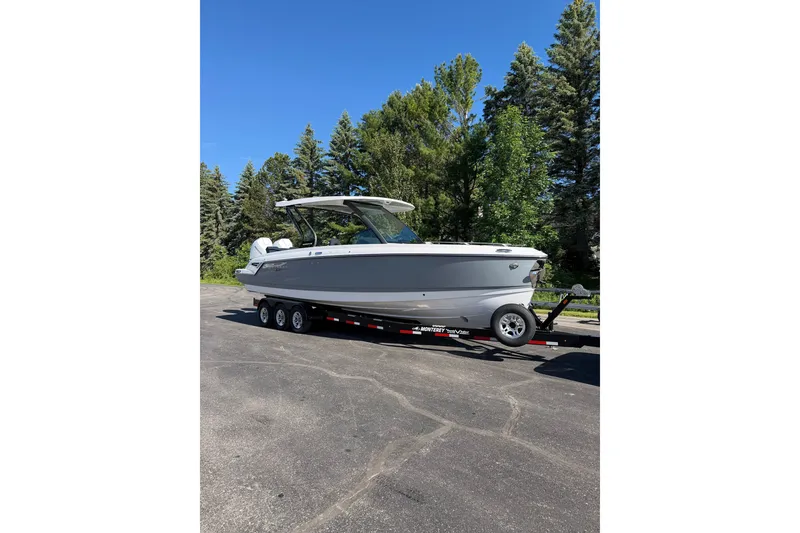 Slide: The Image of 2027 Monterey Elite 30 OB boat on trailer, surrounded by trees and clear blue sky. - 25