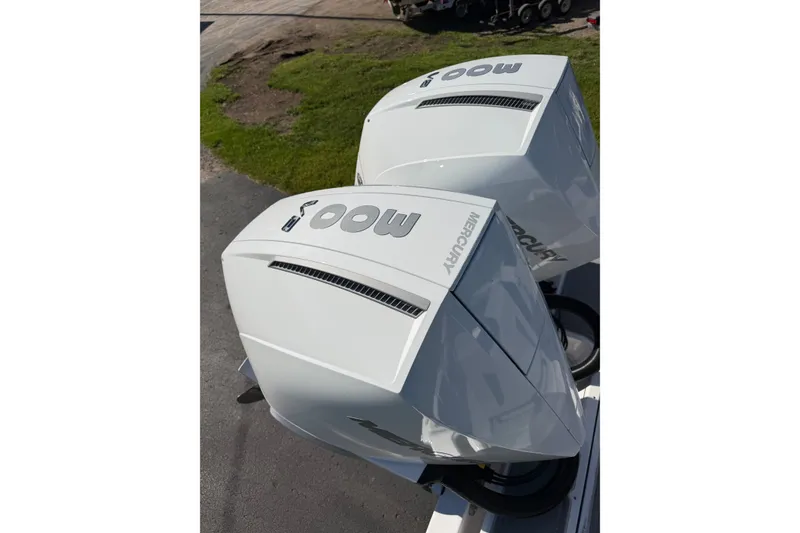 Slide: The Image of Twin Mercury outboard engines on a 2027 Monterey Elite 30 OB boat, parked on pavement. - 6
