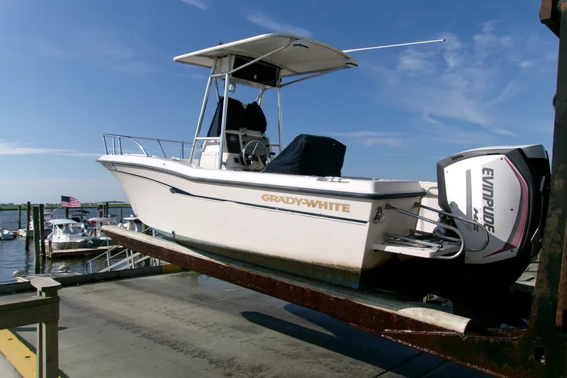 Slide: The Image of 2000 Grady-White Escape 209 boat on dock with Evinrude engine, clear sky background. - 26