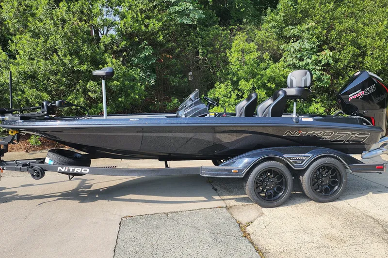 The Image of 2027 Nitro Z19 XL boat on trailer, parked outdoors with lush greenery background. - 1