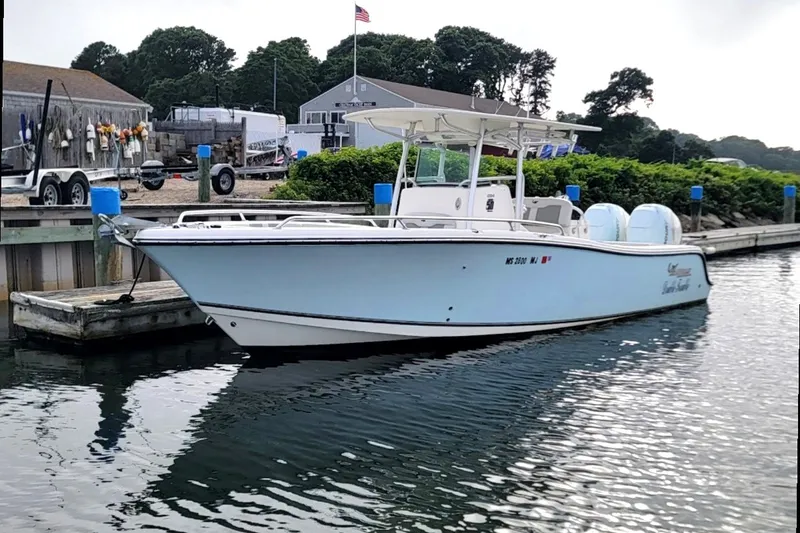 Slide: The Image of 2018 Mako 284 Center Console boat docked at a marina with scenic background. - 29